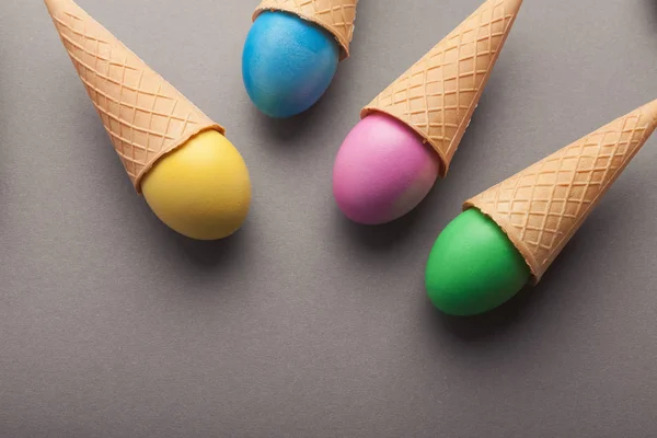 Huevos coloridos de Pascua en conos de gofre sobre fondo gris — Foto de Stock