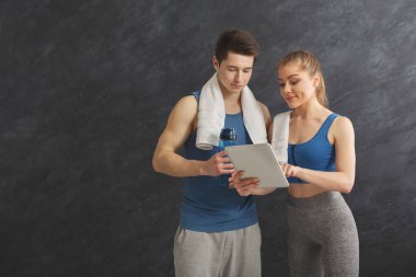 Genç çift spor salonunda egzersiz planı tartışıyor