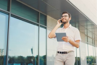 Neşeli işadamı telefon ve tablet açık havada kullanma