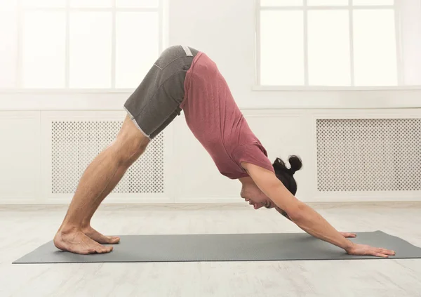 Yoga uitrekken. Jonge man in hond pose — Stockfoto