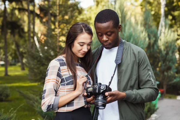 Casal multiétnico assistindo fotos na câmera — Fotografia de Stock