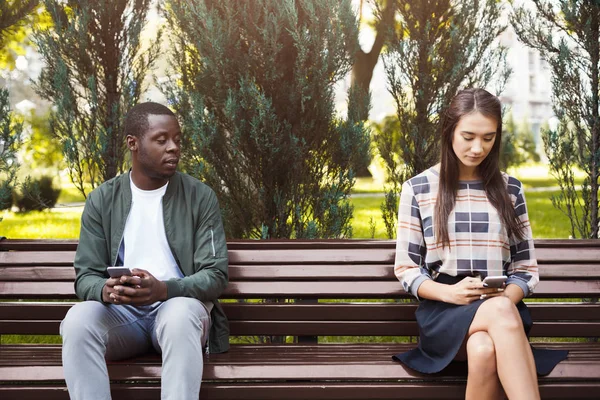 Donna seduta nel parco con l'uomo utilizzando lo smartphone — Foto Stock