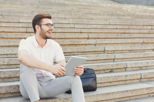 Joven hombre de negocios alegre utilizando tableta al aire libre — Foto de Stock