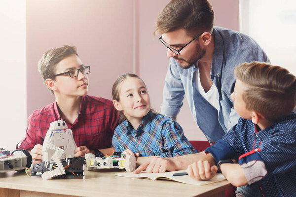 Stem education. Kids creating robots with teacher