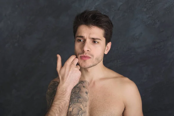 Yakışıklı genç dövmeli adam yüzünü dokunaklı — Stok fotoğraf