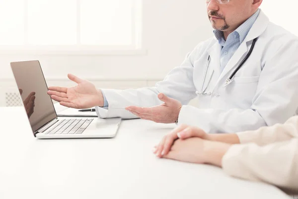 Closeup of doctor and patient sitting at desk