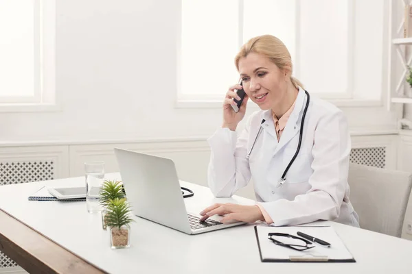 Привлекательный врач разговаривает по телефону с пациентом — стоковое фото