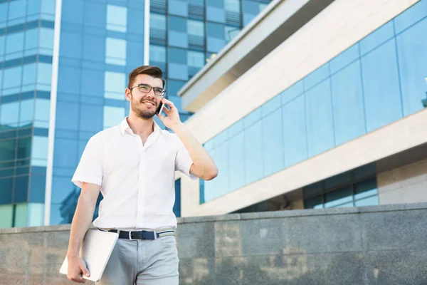 Young happy man making a call and holding tablet outside — Stock Photo, Image