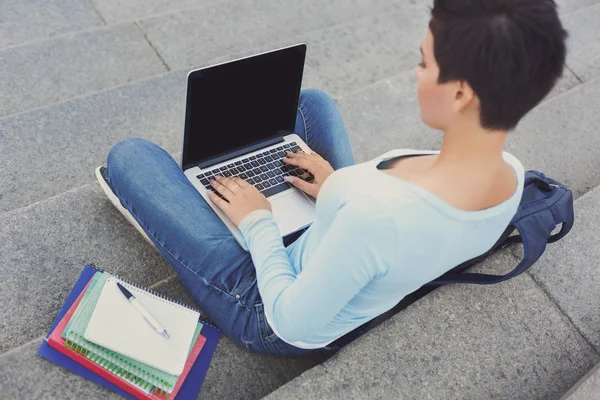 Vrouwelijke student te typen op de laptop en het drinken van koffie buiten — Stockfoto