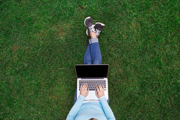 Dizüstü bilgisayar ile yeşil çimenlerin üzerinde parkta oturan kadının Üstten Görünüm — Stok fotoğraf