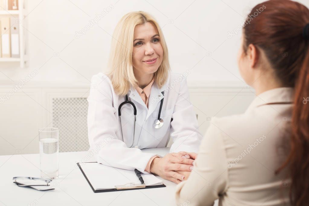 Happy doctor consulting woman in hospital