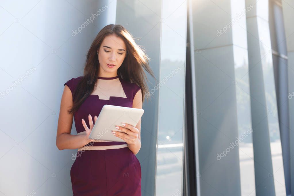 Serious businesswoman working with tablet outdoors