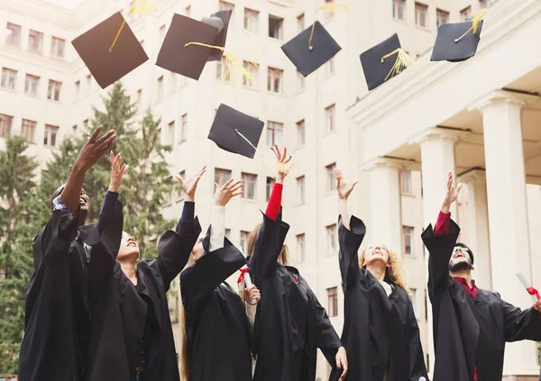 Um grupo de graduados jogando bonés de formatura no ar — Fotografia de Stock