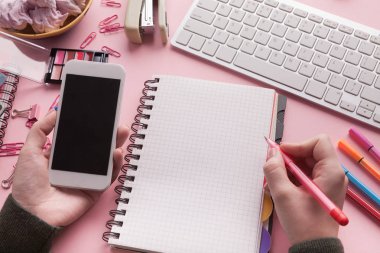 Kadının elleri Smartphone holding ve spiral Not Defteri'nde yazma