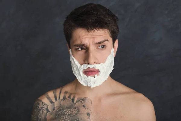 Serious tattooed man with foam on face — Stock Photo, Image