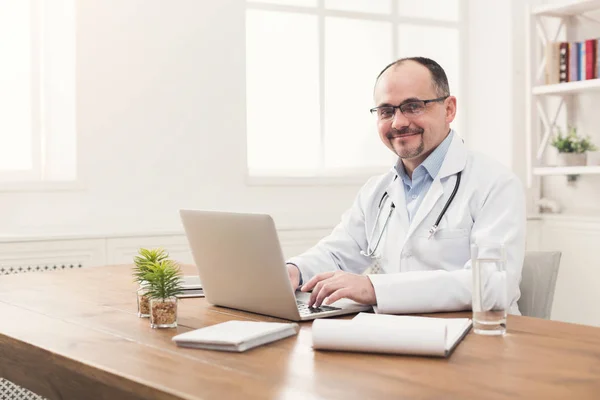 Muotokuva lääkäri lasit istuu työpöydällä — kuvapankkivalokuva