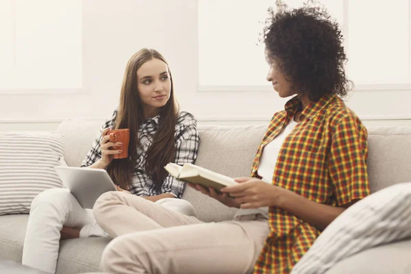 Zwei Freundinnen lesen Buch und E-Book zu Hause — Stockfoto