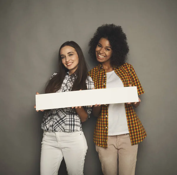 Twee vriendinnen houden van lege witte spandoek — Stockfoto