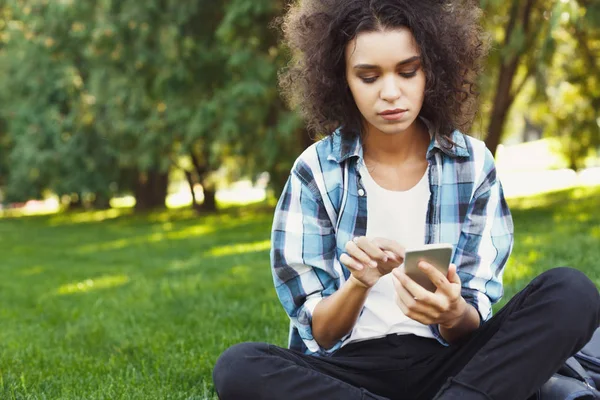 Mujer joven feliz usando el teléfono inteligente en el parque —  Fotos de Stock