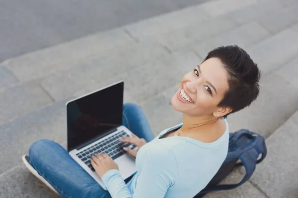 Bella ragazza dai capelli corti seduta con il computer portatile fuori — Foto Stock