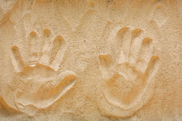 Handprints on yellow beach sand, top view