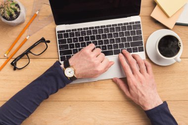 Ahşap masa dizüstü bilgisayarda yazarak adam.