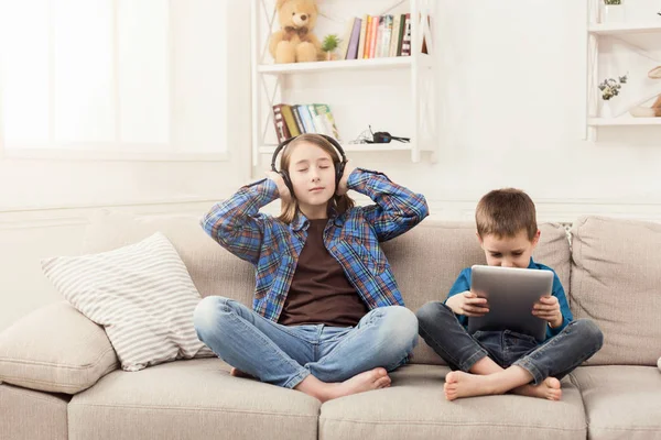 İki çocuk, evde kanepede müzik dinlemek — Stok fotoğraf