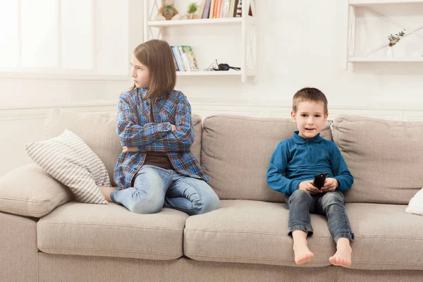 Two kids with remote control on couch at home — Stock Photo, Image