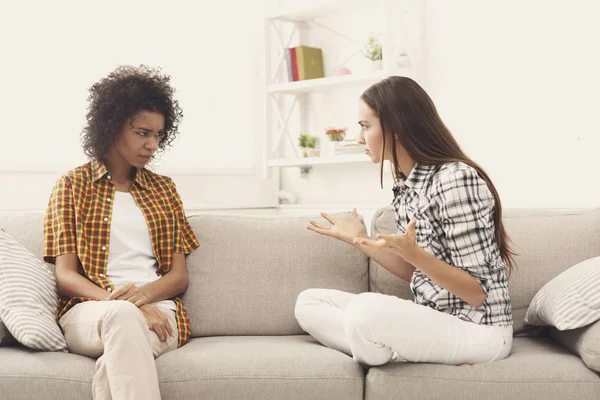 Two female friends sitting on sofa and arguing — Stock Photo, Image