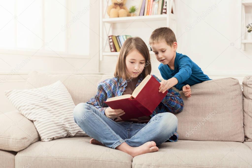 Young girl reading book for her brother