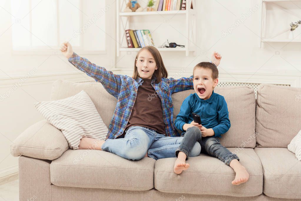 Happy children watching TV at home