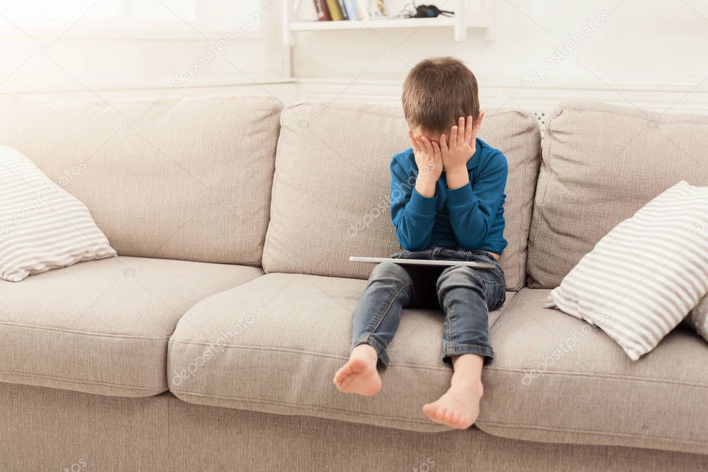 Crying boy with digital tablet at home
