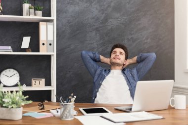 Genç işadamı ofiste dizüstü bilgisayar ile rahat