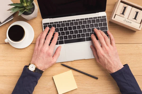 Homem digitando no computador portátil na mesa de madeira . — Fotografia de Stock