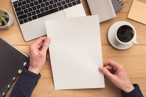 Hombre sosteniendo hoja de papel en el lugar de trabajo — Foto de Stock