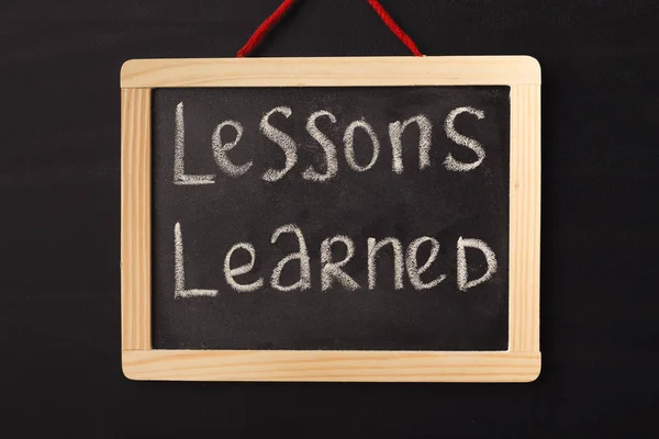 Word lessons learned written on miniature chalkboard — Stock Photo, Image