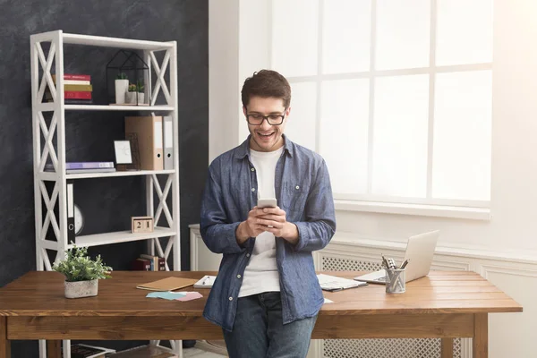 Розслаблений молодий бізнесмен використовує мобільний в офісі — стокове фото
