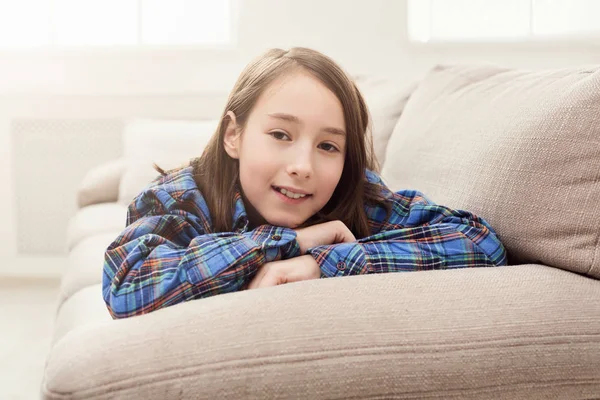 Glückliches kleines Mädchen zu Hause auf dem Sofa liegend — Stockfoto