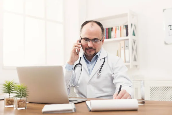 Счастливый доктор разговаривает по телефону со своим пациентом — стоковое фото