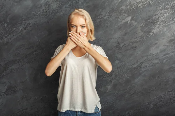 Ung kvinna som täcker munnen med händerna — Stockfoto