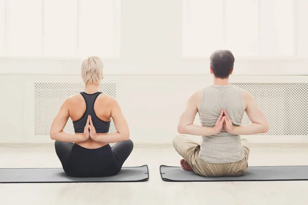 Young couple in yoga class, back stretching