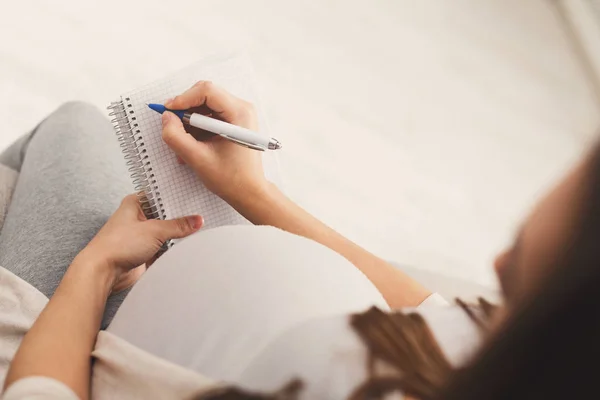 Pregnant woman writing names for her baby