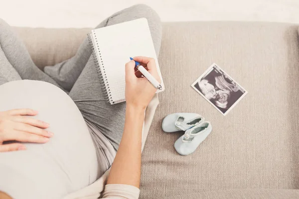 妊娠中の女性は彼女の赤ん坊の名前を書く — ストック写真