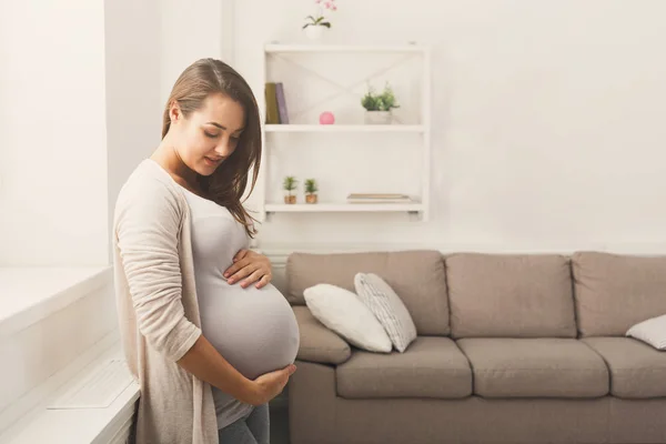 Pegnant mujer acariciando su vientre en casa — Foto de Stock