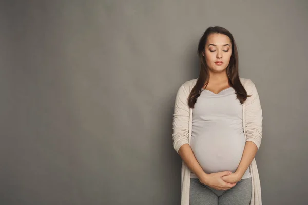 Mujer embarazada con los ojos cerrados en el estudio —  Fotos de Stock
