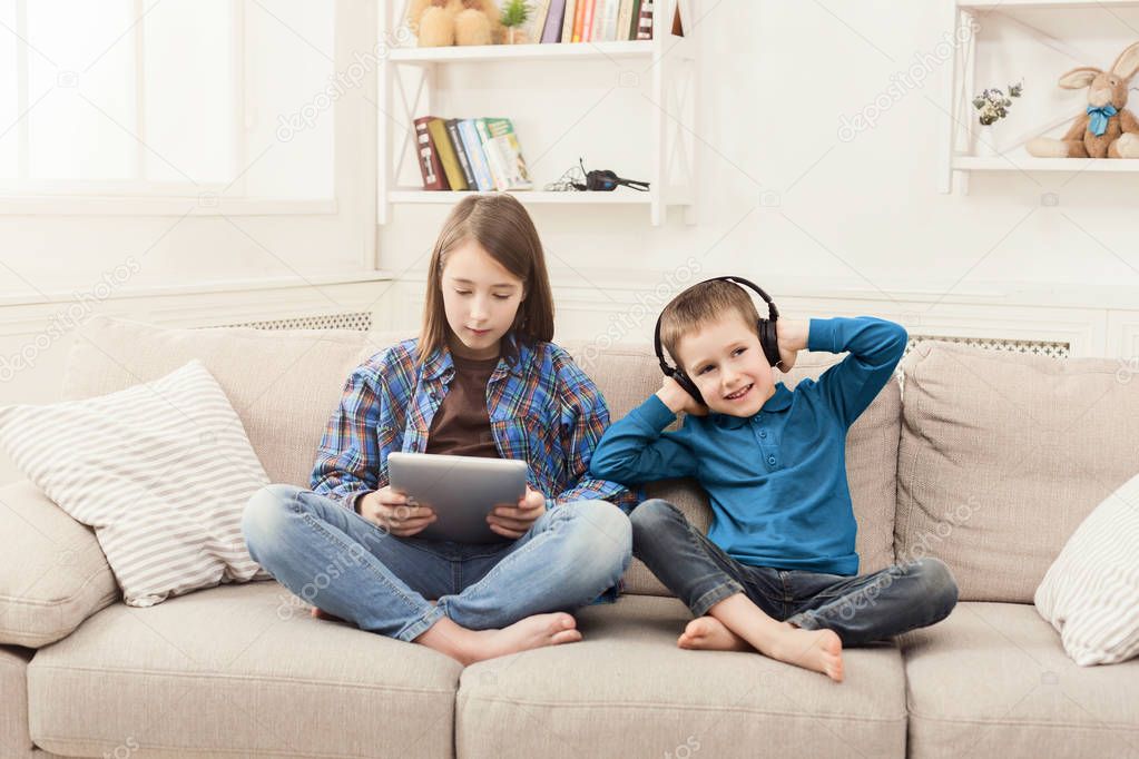 Two kids listening music on couch at home