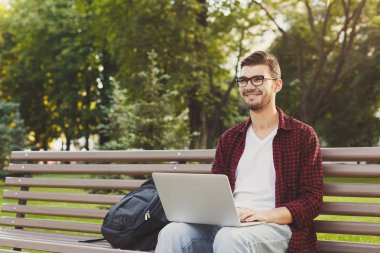 Mutlu genç adam ile dizüstü bilgisayar açık havada