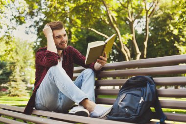 genç adam açık havada bir kitap okuma