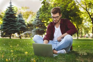 Bir dizüstü bilgisayar açık havada kullanma yakışıklı genç