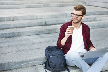 Bir dizüstü bilgisayarda çalışan ve içme kahve dışında öğrenci